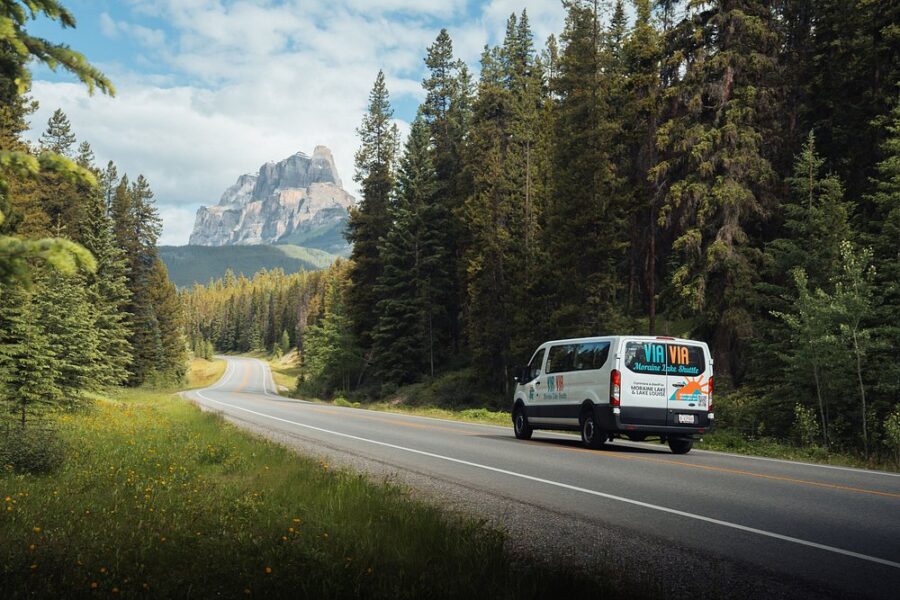 Van travels down a scenic road on Bow Valley Parkway, framed by a stunning mountain backdrop in Canada.