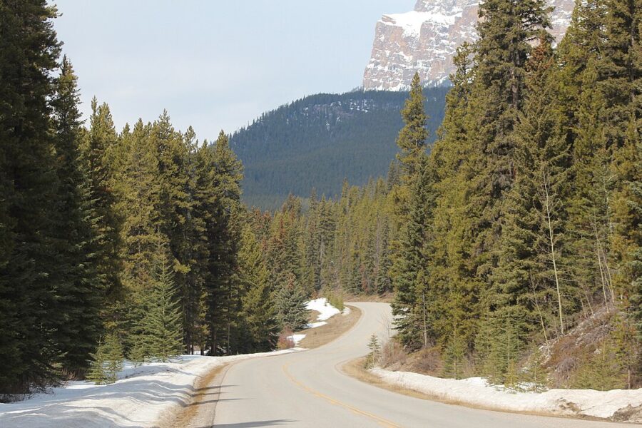Bright blue sky with soft white clouds above the scenic Bow Valley Parkway in Banff National Park.