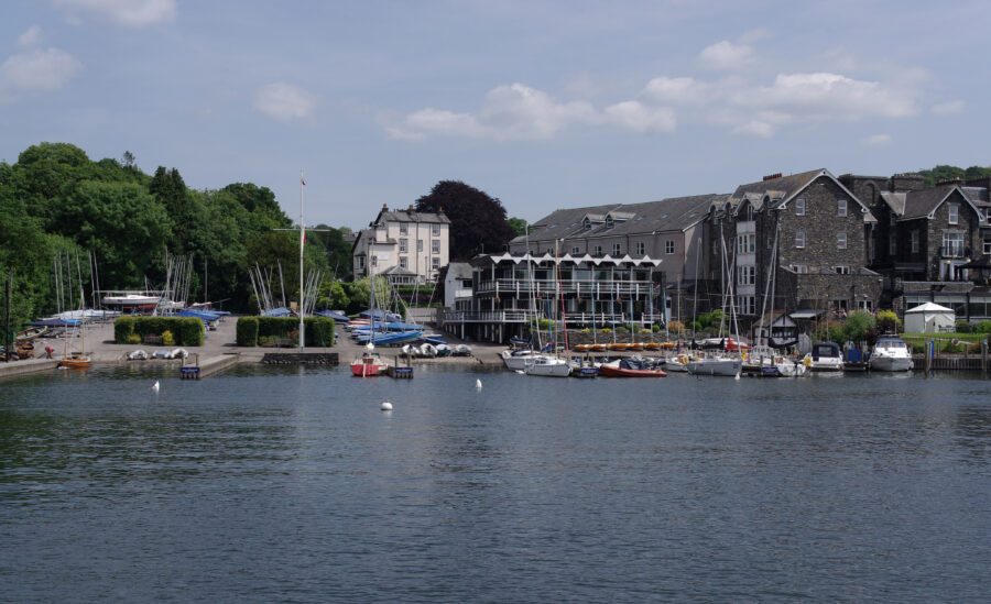 Tranquil waters of Bowness-on-Windermere, England, reflecting the sky and framed by scenic landscapes.