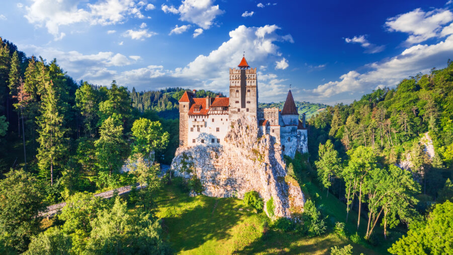 Bran Castle in Transylvania, Romania, known for its association with Dracula, stands majestically against a mountainous backdrop.