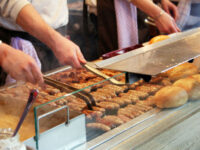 Hot dog stall in Germany showcasing bratwurste being prepared on a grill, with a vibrant atmosphere and eager customers