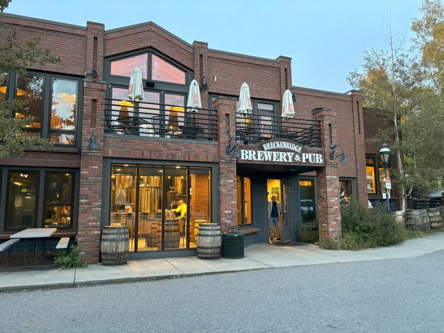 Exterior view of Breckenridge Brewery & Pub, featuring a rustic facade and outdoor seating area surrounded by trees.
