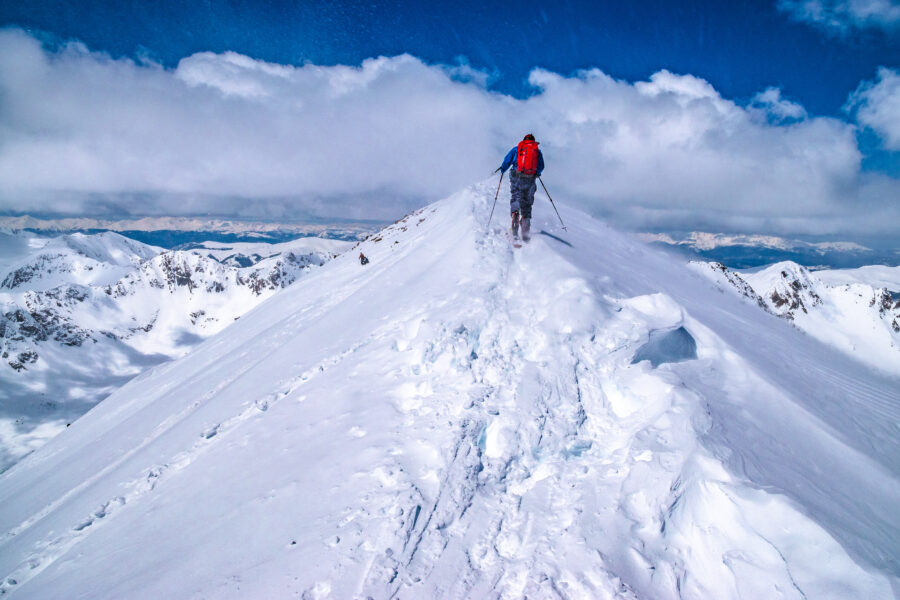 Hiker ascending Quandary Peak in Breckenridge, Colorado, surrounded by rocky terrain and morning sunlight