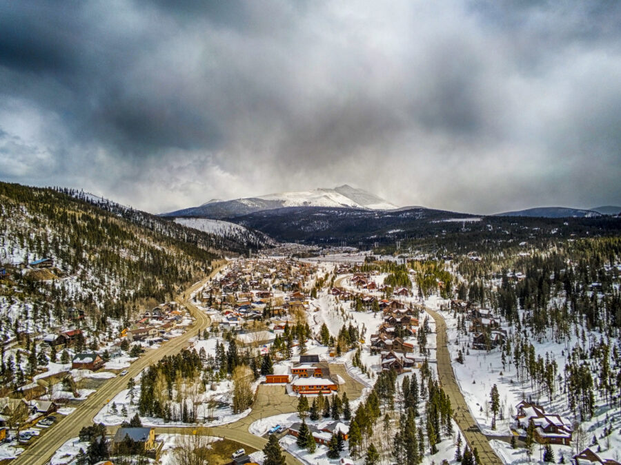 The sun sets dramatically over Breckenridge, Colorado, illuminating the ski resort town with warm hues and a serene atmosphere