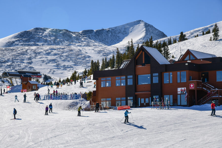 Breckenridge Ski Resort lodge scene featuring skiers and snowboarders on a clear winter day with ideal weather for outdoor activities