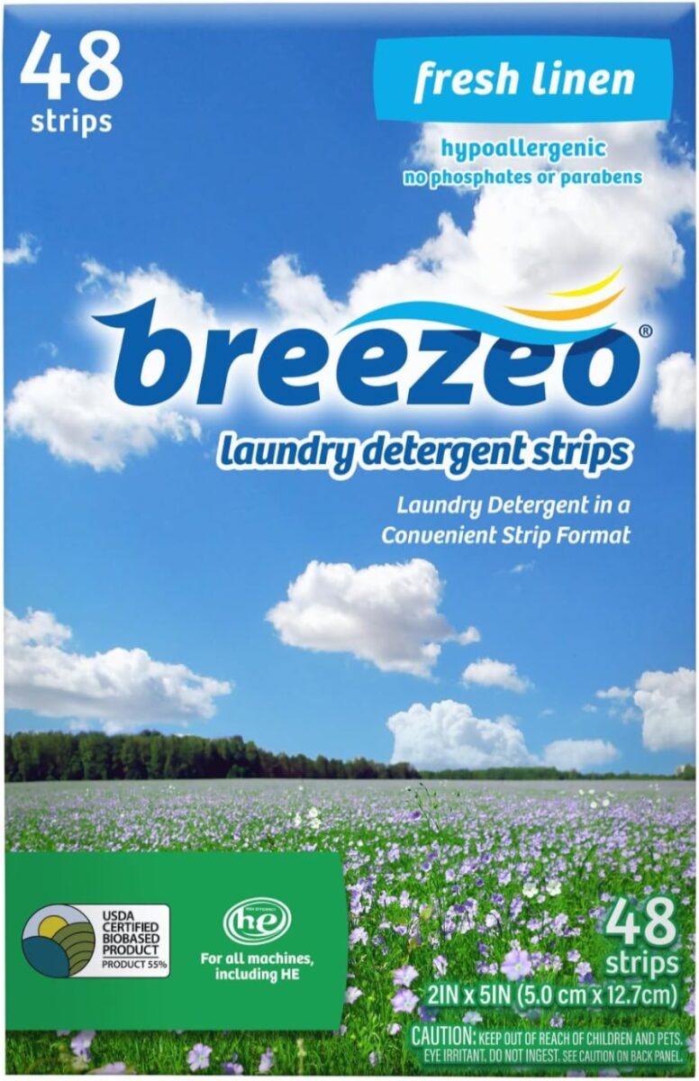 Hands holding a box of lavender-scented travel laundry detergent sheets, displaying eco-friendly icons and text like “Goodbye heavy plastic jugs.”