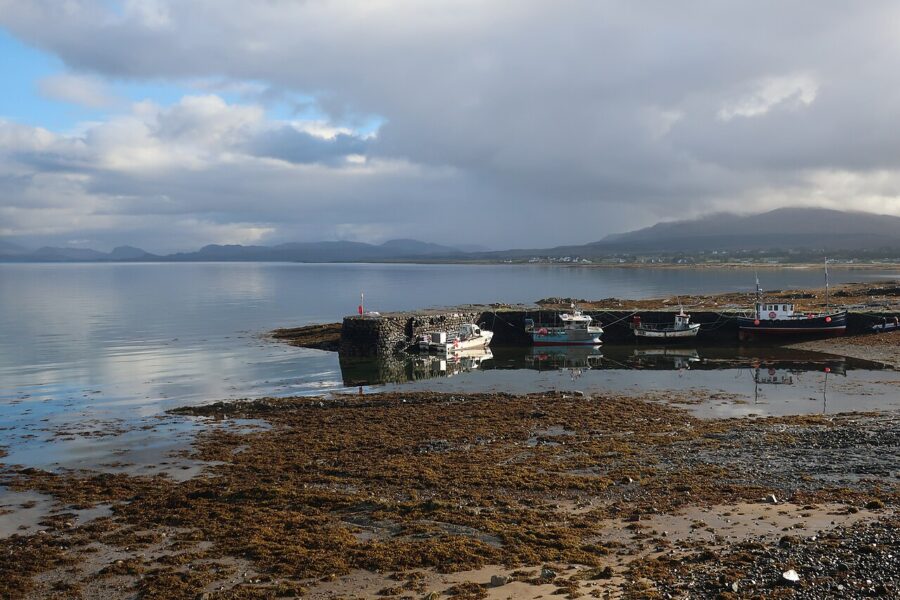 Scenic view of Broadford, Isle of Skye, featuring a calm body of water with boats moored at the dock.
