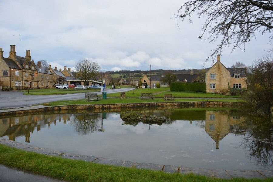 Serene pond in front of a house, featuring a tree in the center, located in Broadway, Cotswold, England.