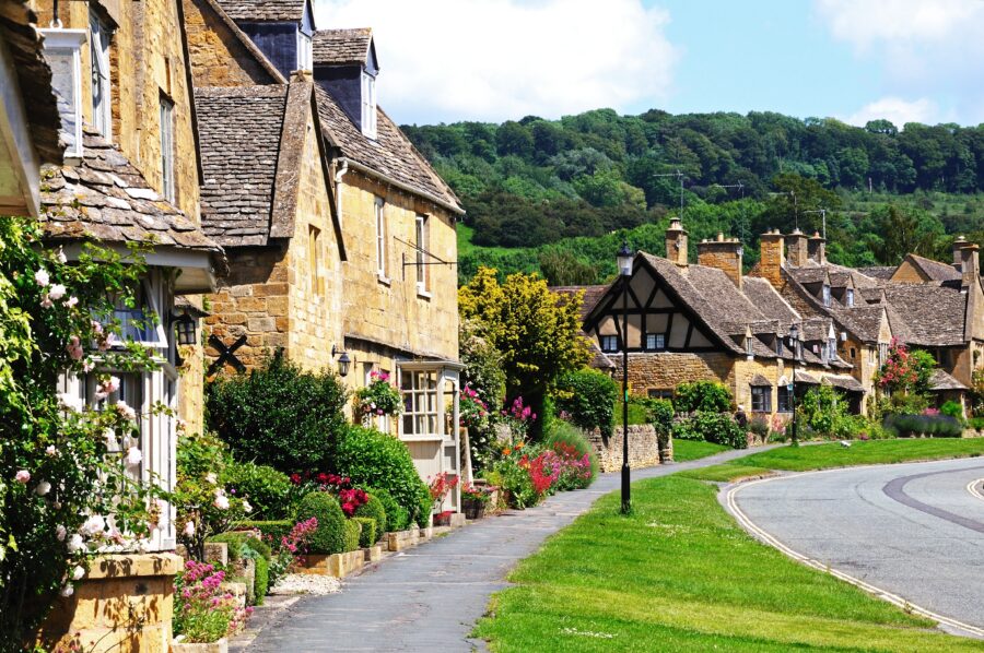 Scenic view of Broadway Cotswolds Cottages along High Street, featuring quaint buildings and lush greenery