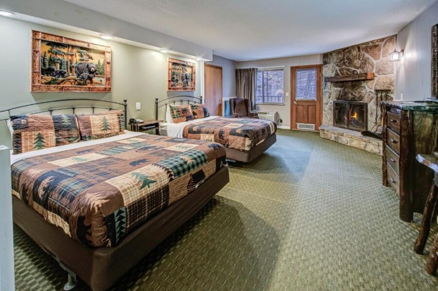 Room at Brookside Lodge, Gatlinburg, with two beds, a fireplace, and a television for a comfortable stay.