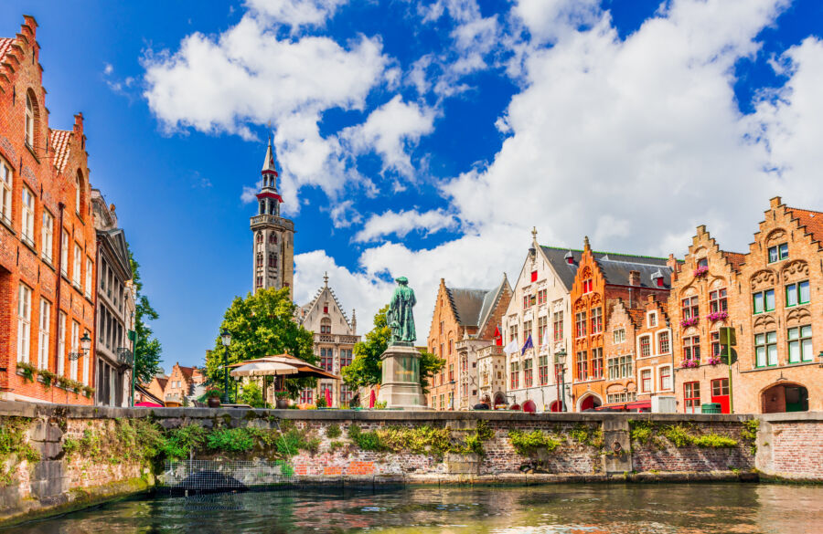 Scenic view of Bruges, Belgium, showcasing historic architecture and picturesque canals under a clear blue sky.