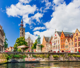 Panoramic view of Bruges, Belgium, showcasing medieval architecture and iconic towers under a sunny sky.