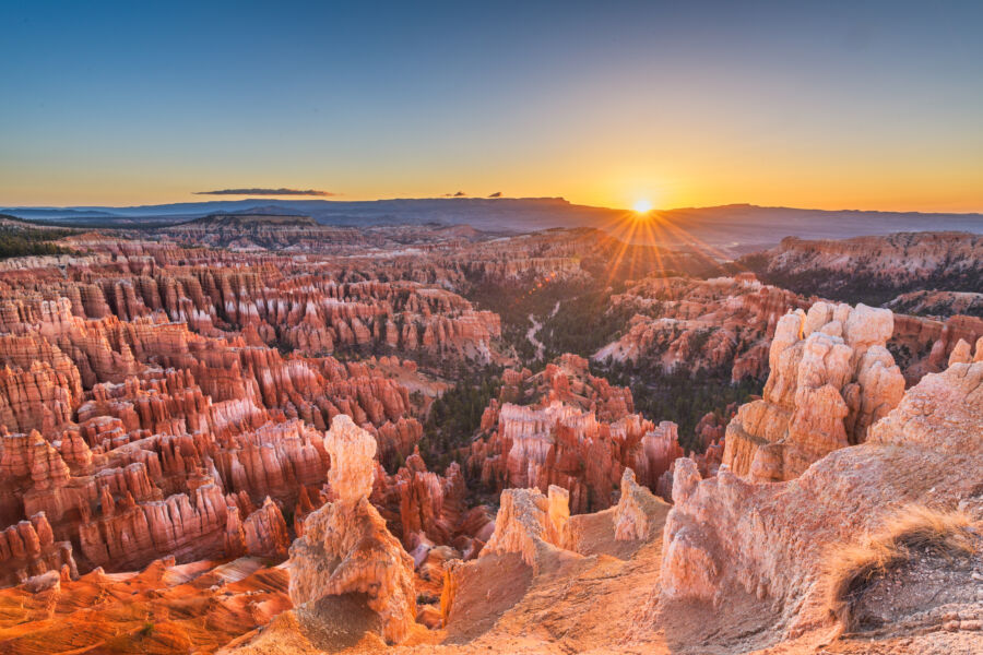 Sunset over Bryce Canyon National Park, showcasing vibrant orange and purple hues illuminating the unique rock formations