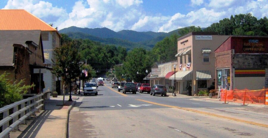 Town street in Bryson City, North Carolina, featuring cars parked along both sides amidst quaint buildings.