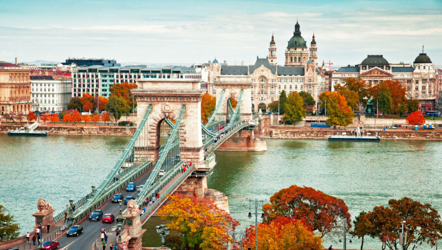 Aerial view of Budapest in autumn, showcasing vibrant fall foliage and iconic landmarks against a clear blue sky