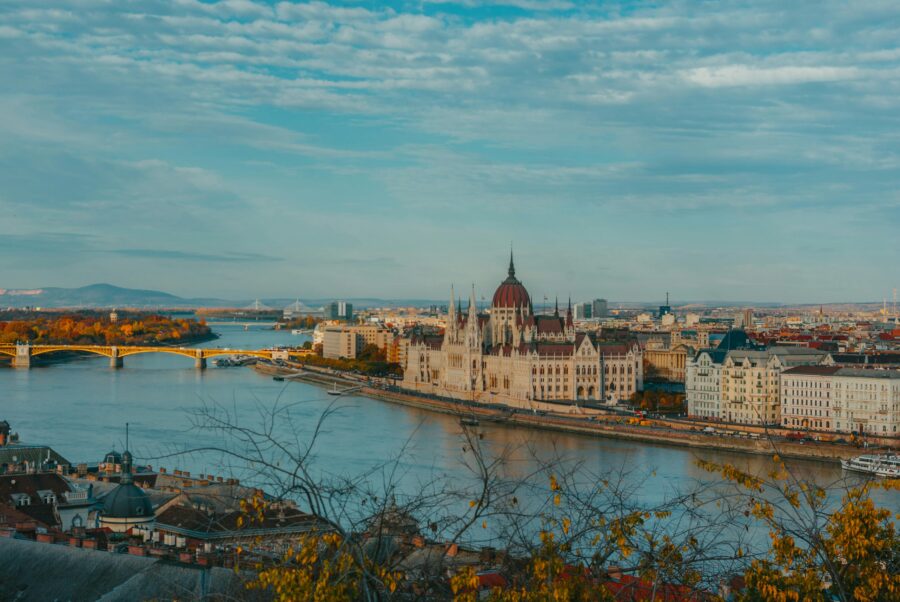 Budapest Parliament and Danube River skyline with bridge and reflections.