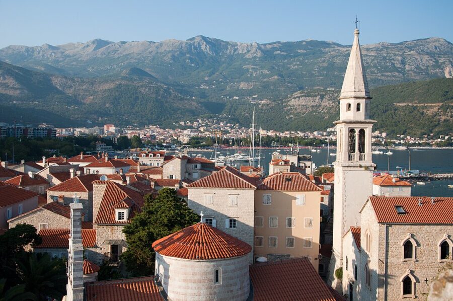 Scenic view of Budva, Montenegro, showcasing a church tower and a mountain in the distance.