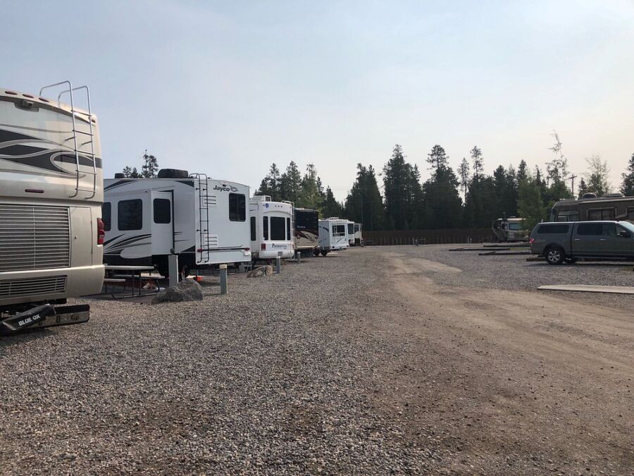 Several RVs are parked in a gravel lot at Buffalo Crossing RV Park, showcasing a popular camping destination.