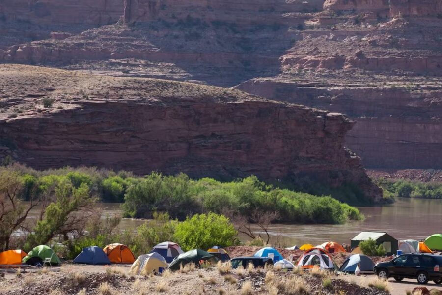 Tents arranged near a river at Bullfrog RV & Campground, with a peaceful natural setting in the background.
