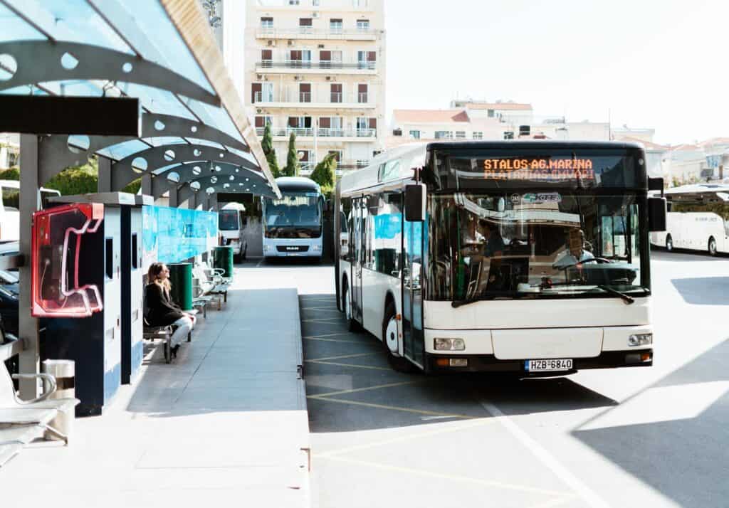 Chania central bus station with buses and passengers on sunny platform.
