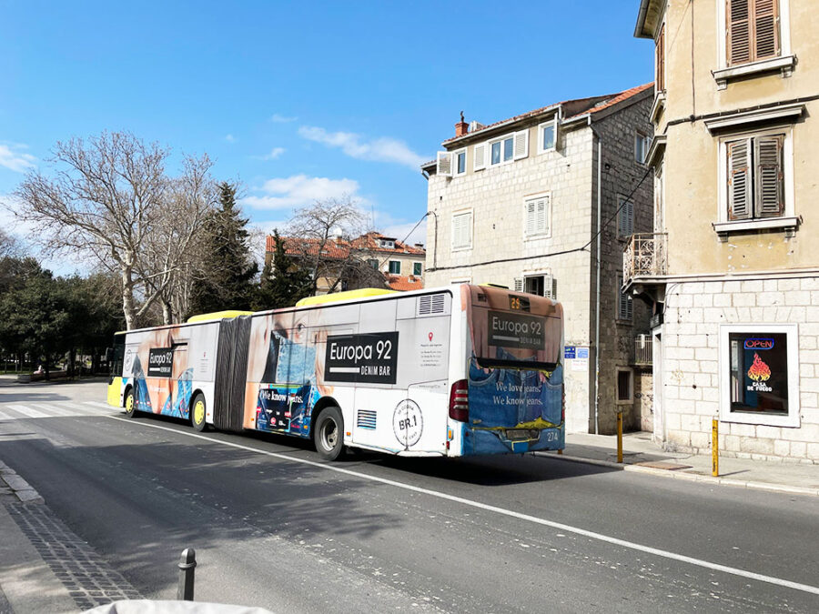 Bus advertising Europa 92 Denim Bar on vibrant European street scene.