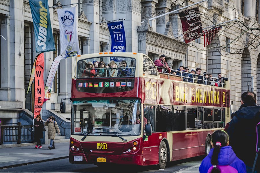 Double-decker tour bus in New York City with historic building backdrop.
