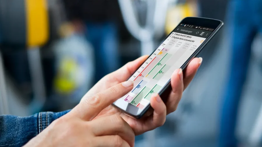 Person checking public transport app on smartphone in bus or train setting.