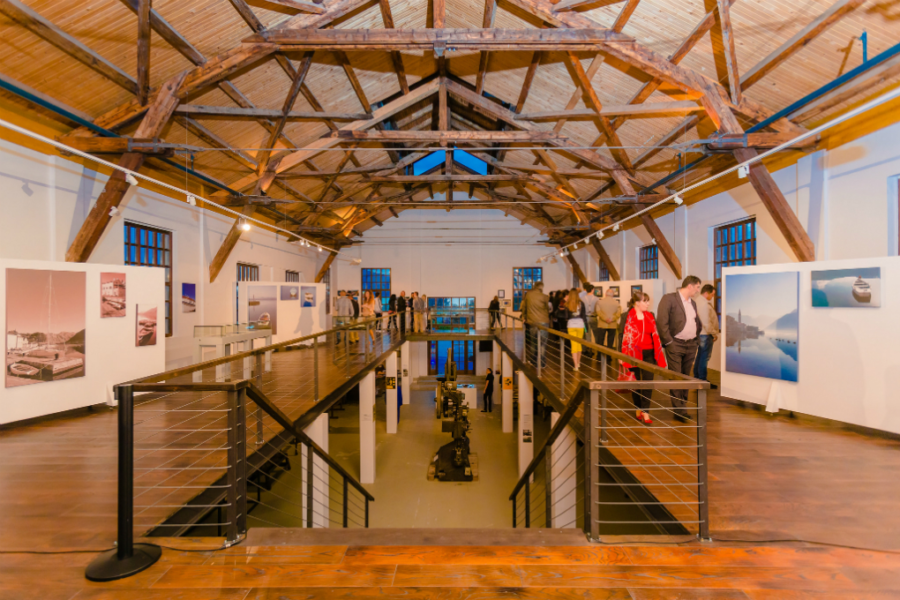 Expansive art gallery showcasing maritime-themed photographs, scenic landscapes, and lively visitor interactions.