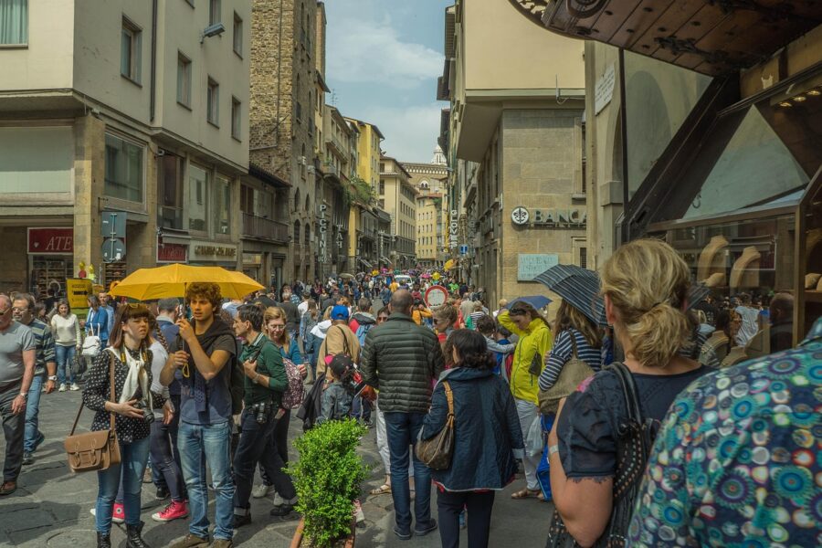 Bustling urban street scene with tourists, shops, historical architecture, and vibrant atmosphere.