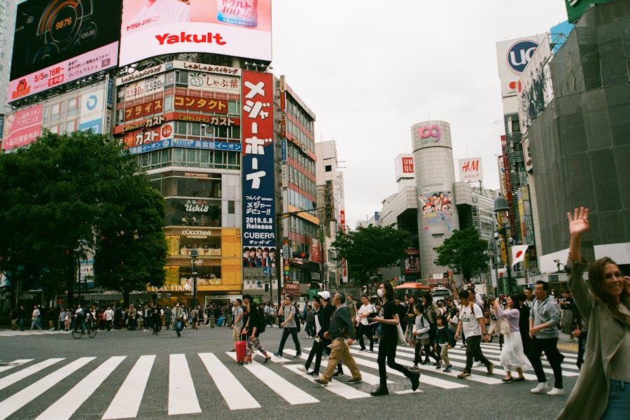 Bustling Tokyo city intersection with diverse pedestrians, advertisements, and modern architecture.