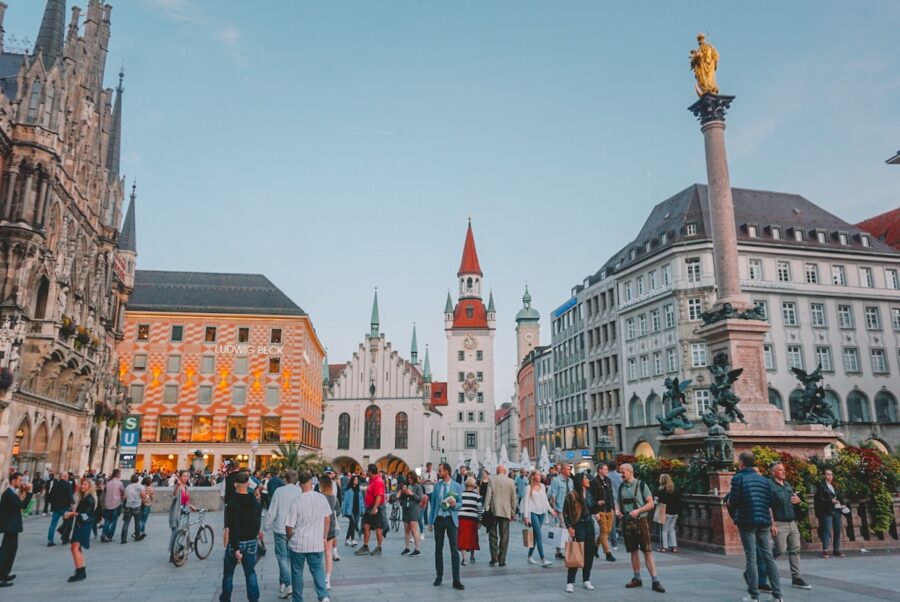 Bustling Munich Marienplatz square at dusk with historic architecture and lively crowd.