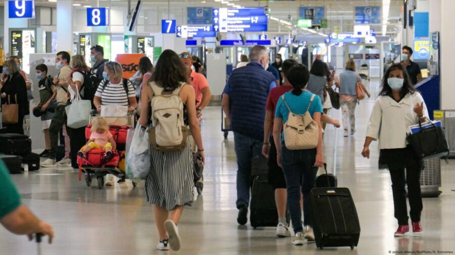 Travelers navigating a lively, bustling airport terminal with masks and luggage.