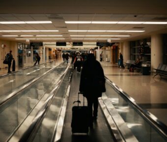 Bustling airport terminal with travelers, bright lights, and high ceilings at night.