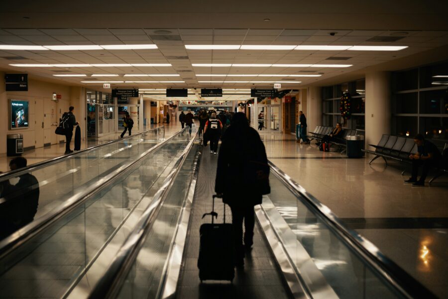 Bustling airport terminal with travelers, bright lights, and high ceilings at night.