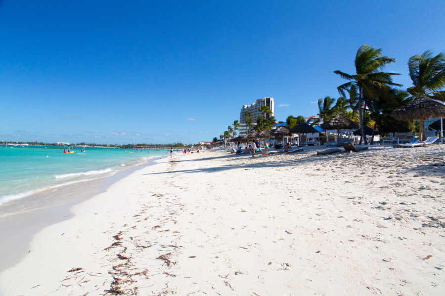 Scenic view of Cable Beach in Nassau, Bahamas, featuring soft white sand and clear turquoise waters under a bright sky.