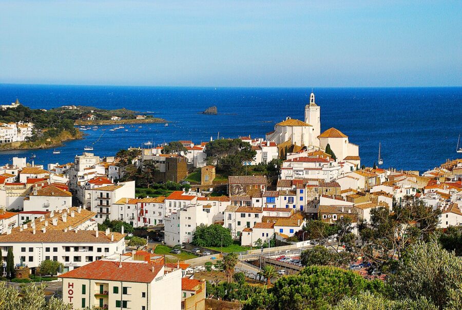 Scenic view of Cadaqués, Costa Brava, featuring a clock tower beside a tranquil body of water.