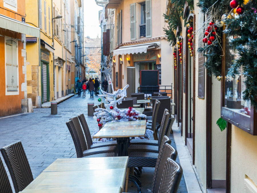 Morning sunlight brightens a charming street in Antibes, France, with small café tables inviting visitors to relax