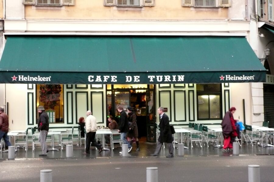 Café de Turin: charming urban café with green awning, outdoor seating, and European architecture.