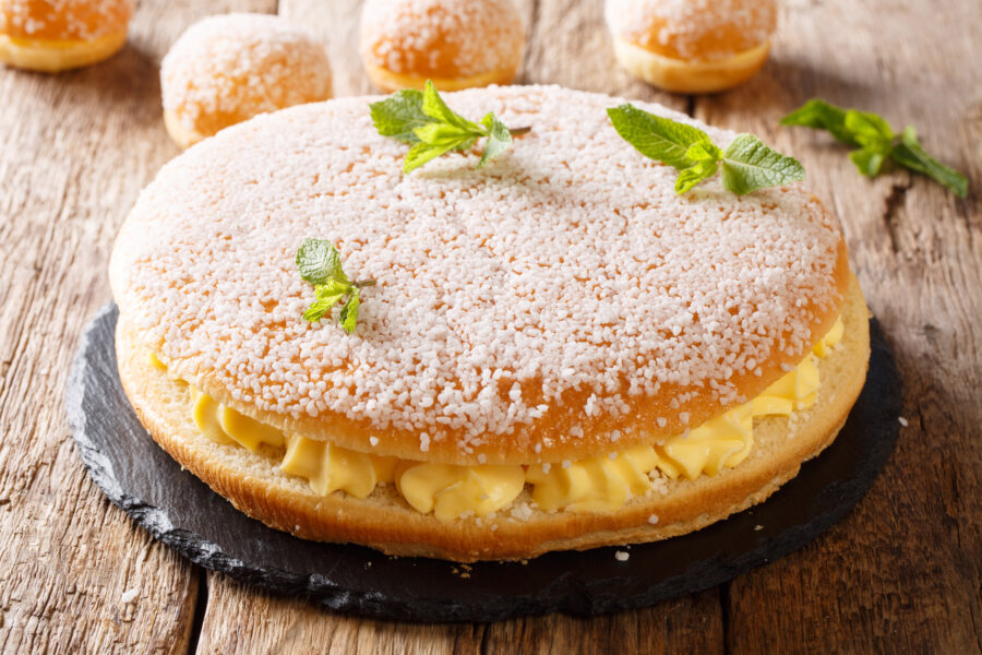 French tropezienne tarte brioche cake with tender cream and pearl sugar close-up. horizontal