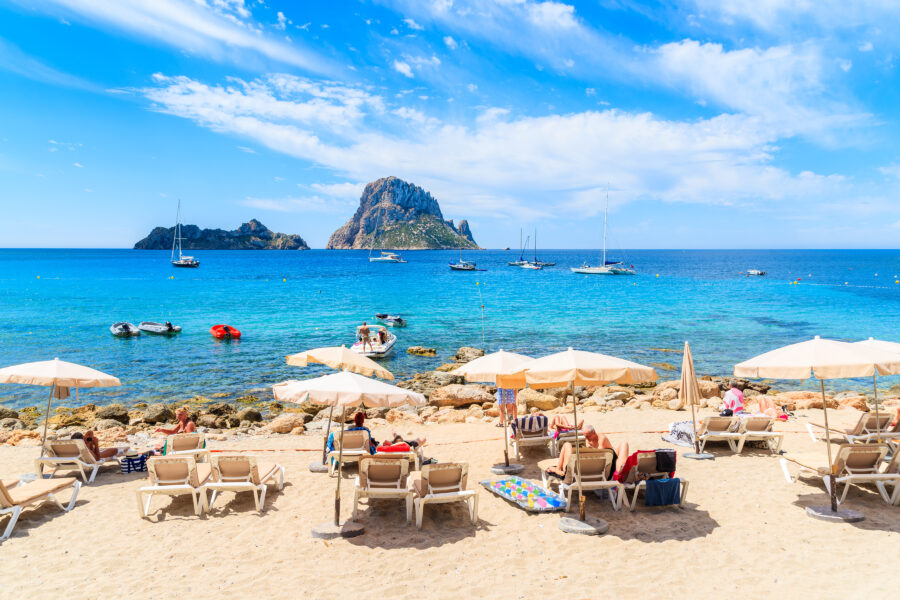 Sunbathers enjoy the warm sun on Cala d'Hort beach, surrounded by the natural beauty of Ibiza, Spain
