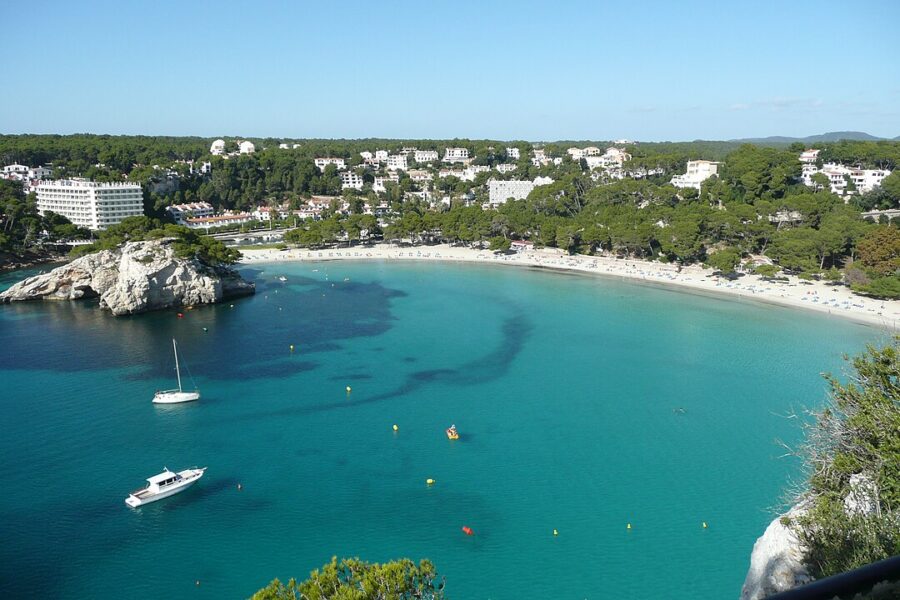 Scenic view of Cala Galdana beach in Menorca, featuring a boat gently floating in the clear blue water.
