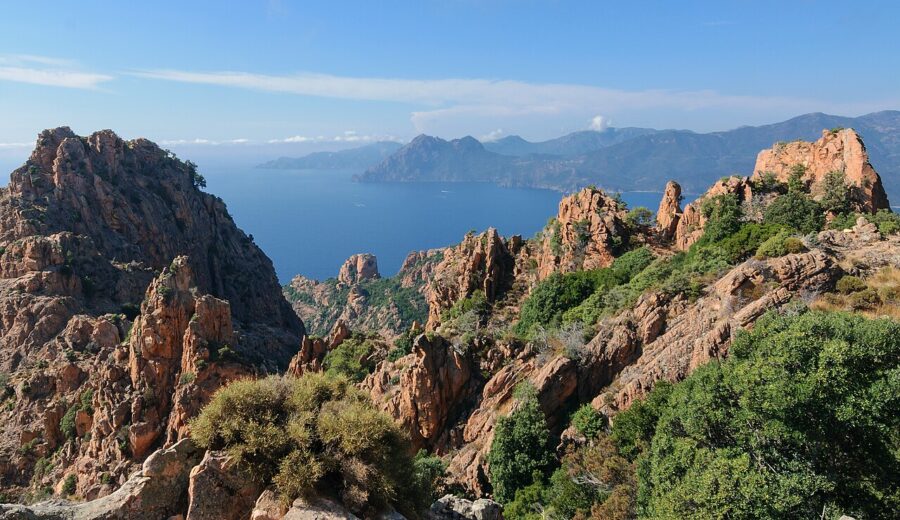 Scenic view from a mountain peak at Calanques de Piana, France, overlooking the sparkling blue ocean below.