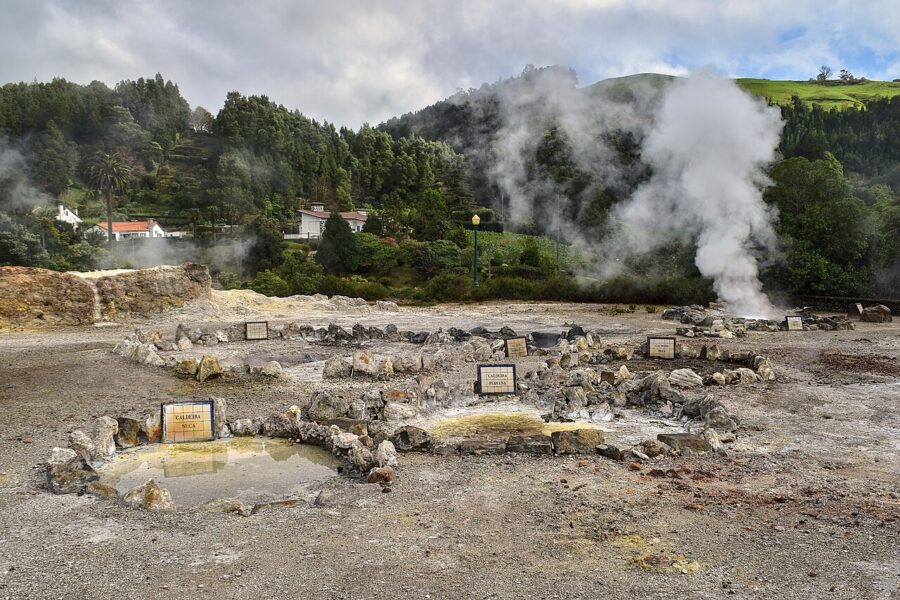 Scenic view of hot springs at Caldeiras das Furnas, São Miguel Island, Portugal, with steam rising amidst vibrant vegetation.