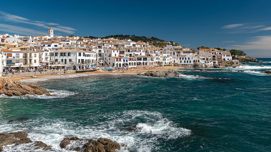 Several boats are moored in a picturesque harbor on the Costa Brava, Spain, reflecting the vibrant coastal scenery.