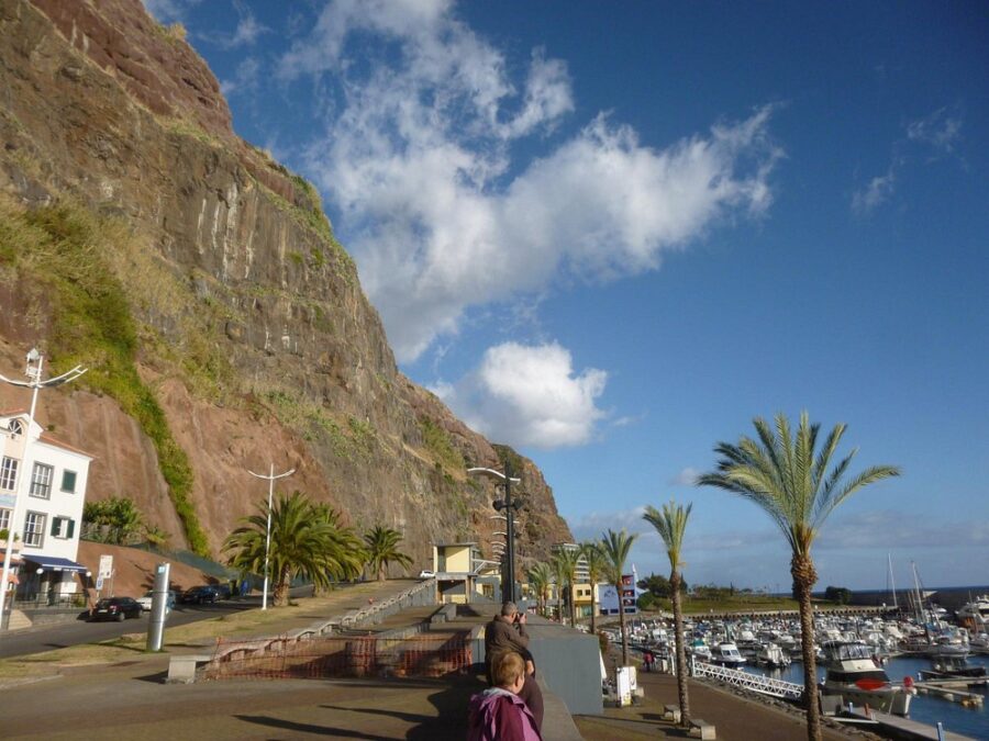 Woman sits on a bench overlooking a cliff in Calheta, Madeira Island, enjoying the scenic view.
