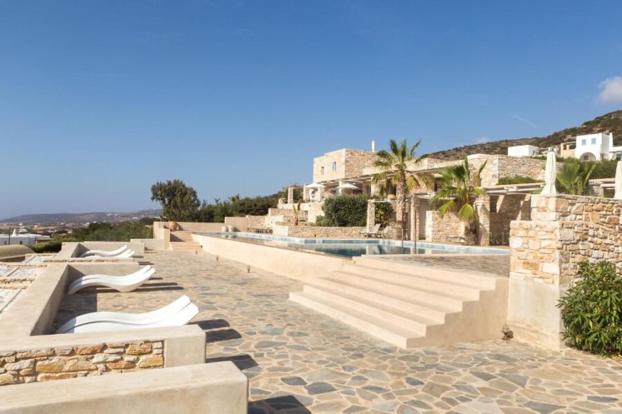 The serene pool and patio area at Calme Boutique Hotel in Greece, featuring sun loungers and lush greenery.