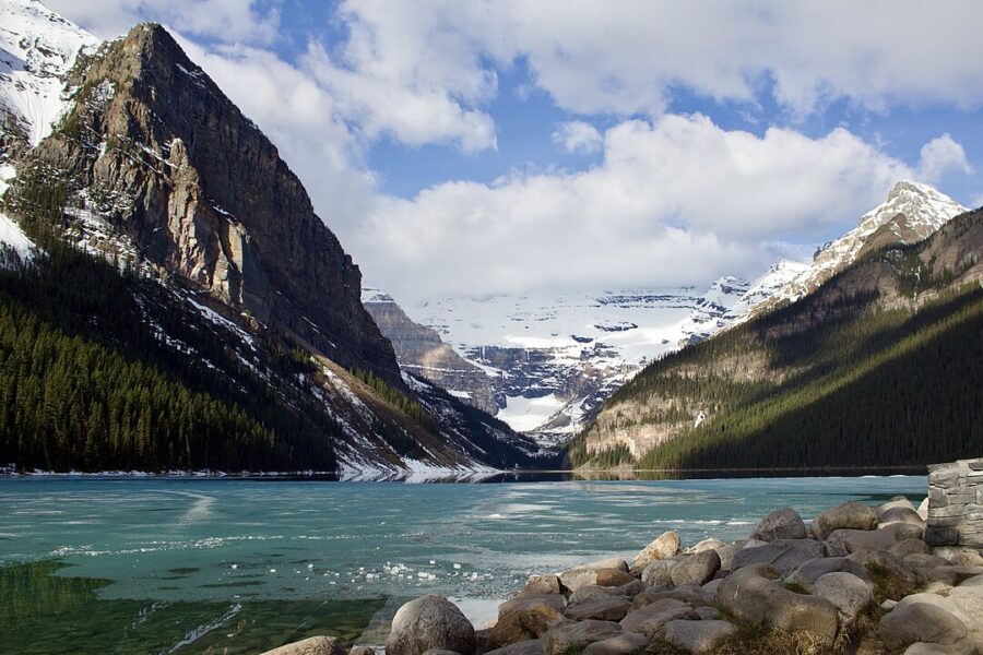 Lake Louise in Banff, Canada, showcasing tranquil waters bordered by rocky shores and vibrant green trees.
