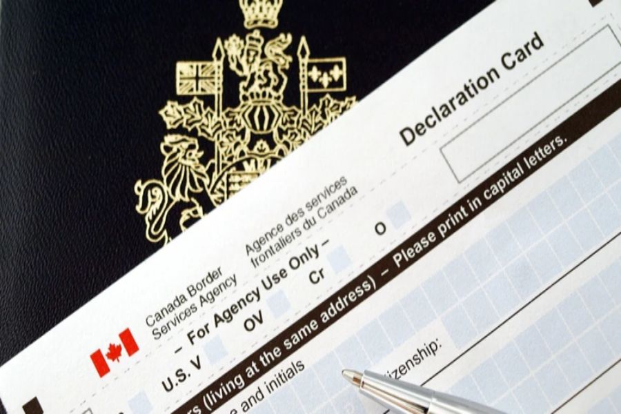 Canadian passport and declaration card for border entry compliance with pen for filling details.