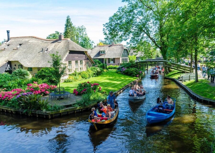 Thatched cottages beside canal boats and gardens in a picturesque English village.