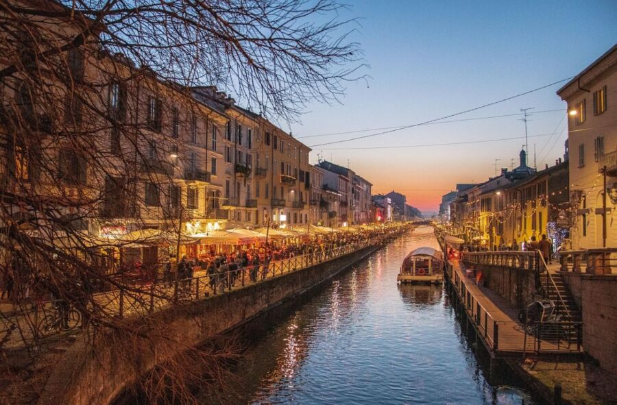 Picturesque Italian canal at sunset with vibrant dining and historic architecture.